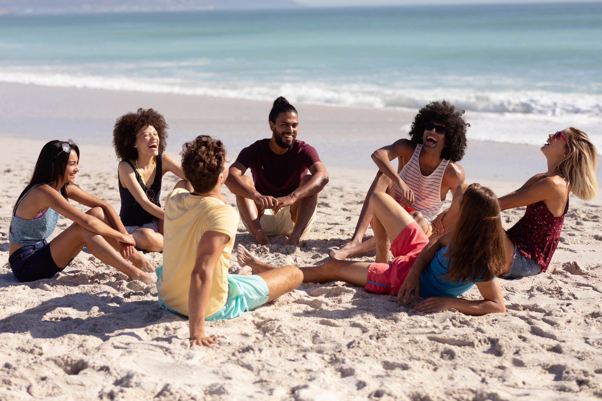 Multi-ethnic group of male and female sitting on the beach